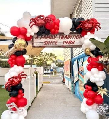 Red, black and white balloon garland with crab foil balloons beside a A Family Tradition Since 1983 sign