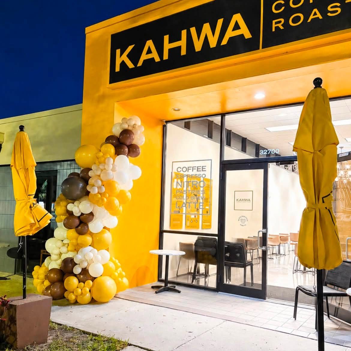 Wide view of the Kahwa Coffee storefront with a brand-matched balloon garland by the entrance